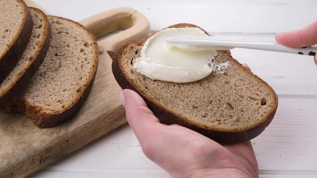 Female hands cooking toast with cream cheese for breakfast.