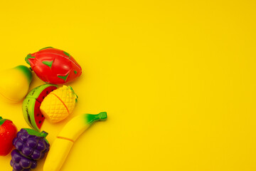 Creative composition of toy fruits and vegetables on a pastel yellow background. Minimum summer concept. Surrealism.