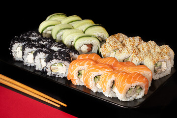 Sushi Sets Uramaki, California, Philadelphia, on a white plate. Festive new year concept. Against a dark reflective background.