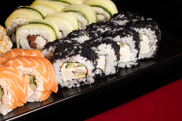 Sushi Sets Uramaki, California, Philadelphia, on a white plate. Festive new year concept. Against a dark reflective background.