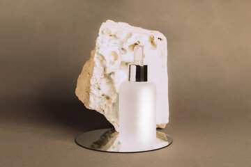 A bottle gel serum of a cosmetic product on the podium made of natural materials