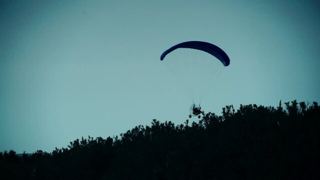 Paragliding. Extreme sport. Paraglider silhouette flying in the evening sky.