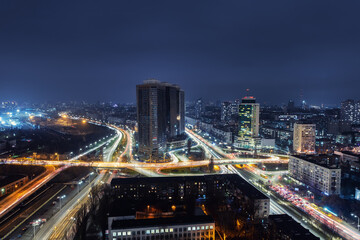 Aerial panoramic drone above roof view of Kiev night traffic road junction scene. Highway city at evening car light trails. Scenic urban skyline cityscape. Busy downtown life of Ukraine capital