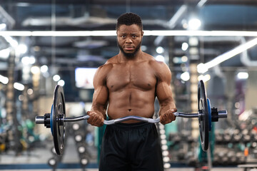 Fototapeta na wymiar Muscular shirtless black guy bodybuilder exercising with barbell at gym