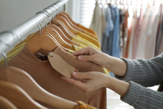 Woman Looking At Price Tag In Modern Clothing Boutique, Closeup