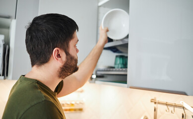 Obraz premium Young man washing dishes in the kitchen.