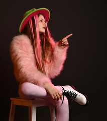 Teenager girl posing in studio wit a chair and a hat over white background