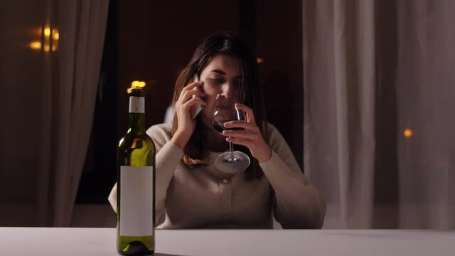 alcoholism, alcohol addiction and people concept - angry drunk woman or female alcoholic drinking red wine and calling on smartphone at home at night