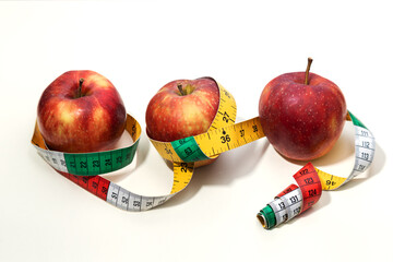Red fresh apples with a yellow measuring tape on bright background. Weight and nutrition control.
