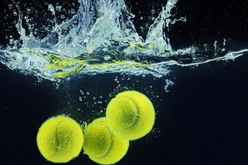 Tennis ball falling in water with a splash against dark background