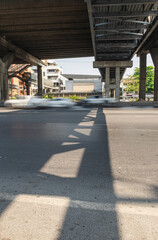 construction pier under highway while vehicle movement on road with shadow lighting on under cross bridge