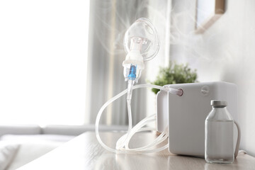 Modern nebulizer with face mask on table indoors. Inhalation equipment