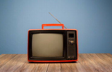 Obraz premium Vintage red old TV on wooden table in the room with blue background