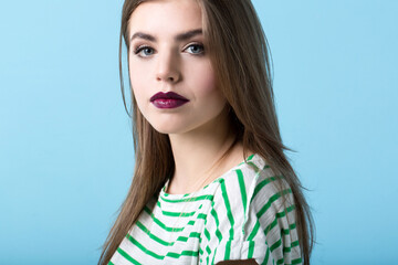 Close-up portrait of a beautiful woman with burgundy lips on a blue background