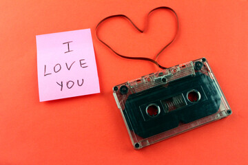 The inscription `` I love you '' with an audio cassette and a heart made of film on a red-orange background