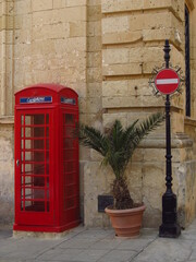 Stara czerwona angielska budka telefoniczna przy murowanej ścianie ze znakiem stop - obrazy, fototapety, plakaty