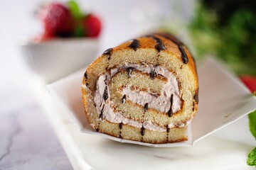 Strawberry Swiss roll or Roulade with cream filling and chocolate drizzle, selective focus