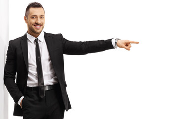 Young businessman leaning on a wall and pointing to the side