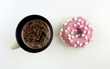 Wooden background with pink donut with small pieces of marshmallow and mug with coffee