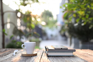 White coffee cup with phone and notebook on wooden table at outdoor