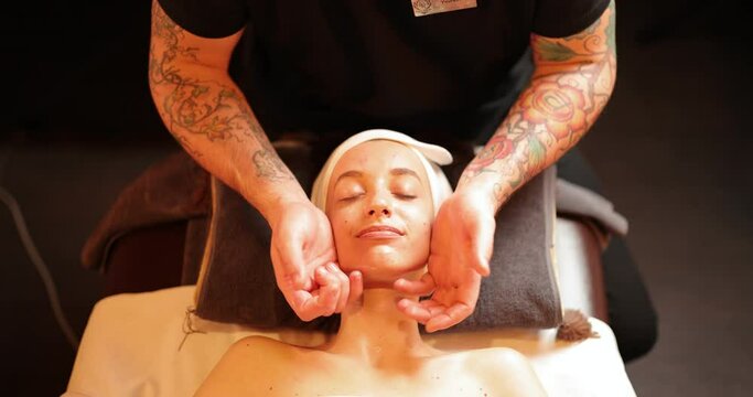Young woman receiving facial relaxing lymph drainage massage in spa