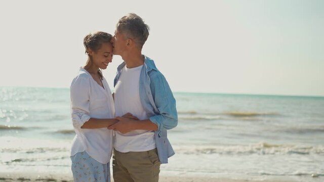 loving couple ambracing, holding hands, kissing and enjoying sunny morning on beach vacation. love, honeymoon, valentines day