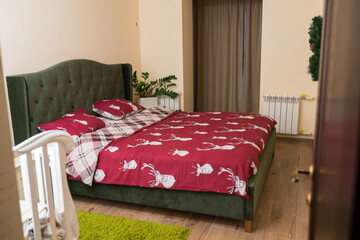 general view of the room with a green double bed and red linens