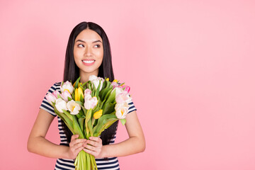 Photo portrait of brunette girl smiling received tulips bunch looking blank space dreamy isolated on pastel pink color background