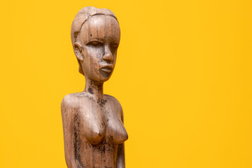 Sideview closeup of female figurine carved out of ebony wood without clothes on holding hands in...