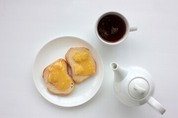 Flat lay food composition with cup of herbal tea, teapot and toast with honey on white table background. Healthy breakfast concept. Top view