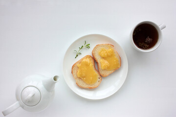 Flat lay food composition with cup of herbal tea, teapot and toast with honey on white table background. Healthy breakfast concept. Top view