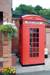Obraz premium Old Red Telephone Kiosk and Colourful Flower Baskets 