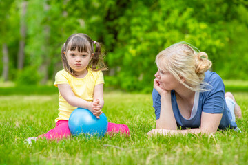 Naklejka na ściany i meble Mother talks with little girl with syndrome down in a summer park