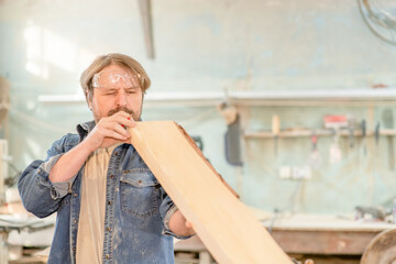 Man looking and choosing wood or testing wood plank in the workshop. Empty space for text