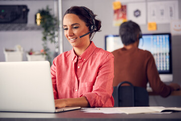 Business Team Wearing Telephone Headsets Talking To Callers In Customer Services Department