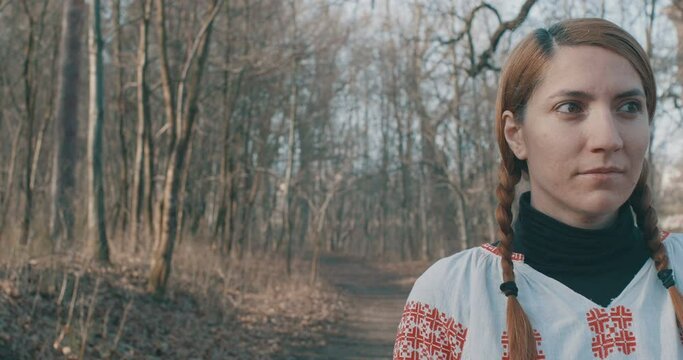 Romanian woman wearing a traditional folk red white blouse in forest.
