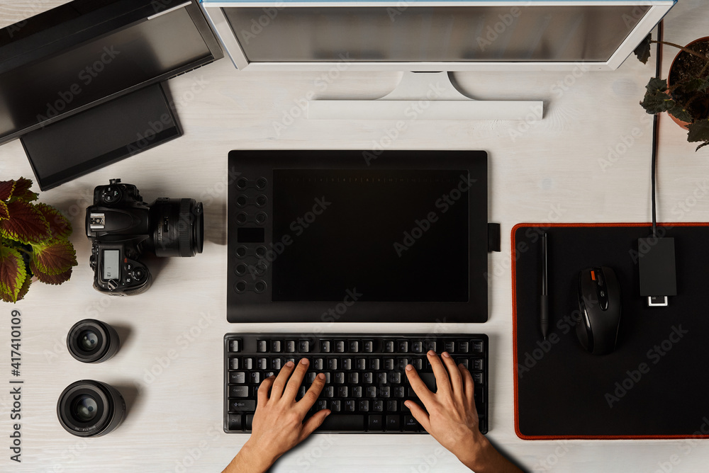 Fototapete top view of hands typing on keyboard in front of two monitors and graphics tablet