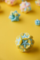 Set of multicolor handmade modular origami balls or Kusudama Isolated on yellow background. Visual...