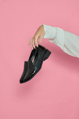 Mulher segurando sapatos em fundo rosa