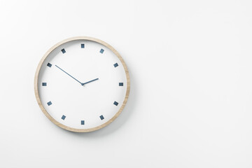 White round wall clock in wooden frame on blank white wall with space for your logo. Mockup