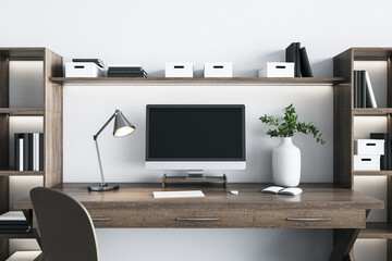 Eco style wooden home workplace with modern computer monitor with blank black screen, white vase, steel lamp and white wall on background. Mockup