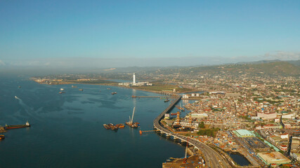 City of Cebu top view, the port in the harbor and cargo ships and a highway with cars near the sea. Philippines, Cebu.