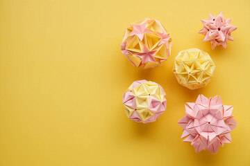 Set of multicolor handmade modular origami balls or Kusudama Isolated on yellow background. Visual...