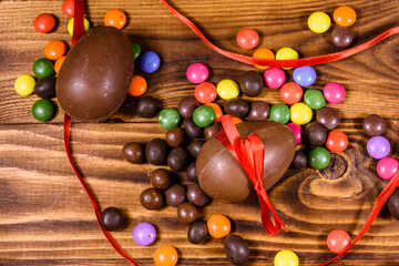Chocolate easter eggs and multicolored candies on wooden table