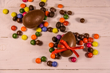 Chocolate easter eggs and multicolored candies on wooden table. Top view