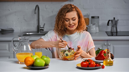 cheerful woman looking at fresh salad in bowl