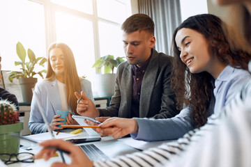 Young designer giving some new ideas about project to his partners in conference room. Business people discussing over new business project in office.