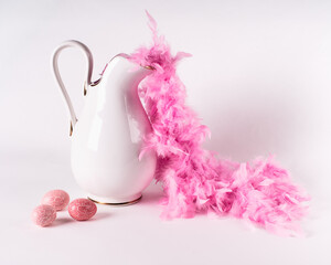 Spring Easter home decor in soft pink and white. A ceramic jug and three pink eggs on a white background.