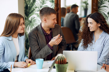 Young designer giving some new ideas about project to his partners in conference room. Business people discussing over new business project in office.