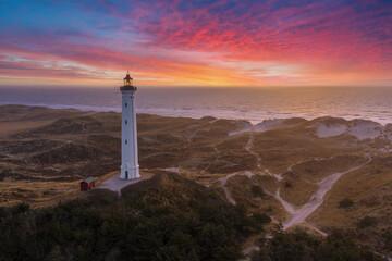 Built in 1906, the 38 meter tall Lyngvig Fyr Lighthouse on the Danish North Sea coast serves as a beautiful tourist attraction amongst the Danish Sand Dunes. - obrazy, fototapety, plakaty